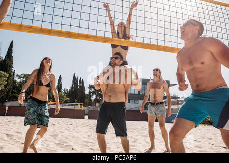 Sommer Urlaub, Sport und Personen Konzept, sportliche junge Menschen genießen mit Beach Volleyball unter der Sonne morgens im Hotel Sport Court Stockfoto