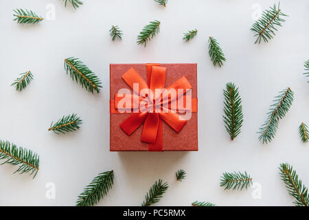 Weihnachten oder Neujahr Geschenk in einem roten Feld. Tannenzweigen in der Nähe von für die Dekoration. Weihnachten Konzept. Stockfoto