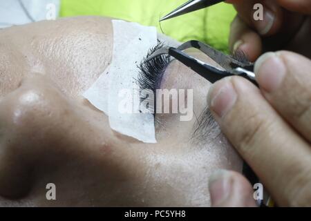 Vietnamesische Beauty Salon. Kosmetikerin Anwendung verlängert die Wimpern zu Frau. Ho Chi Minh City. Vietnam. | Verwendung weltweit Stockfoto