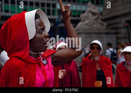 New York, USA., 31. Juli 2018 Einwanderung Aktivist Therese Patricia Okoumou zu Demonstranten außerhalb der USA Custom House, wo Vice President Mike Pence an einem Cyber Security Summit war spricht. Okoumou, einem Kongo Eingeborener, wurde am 4. Juli 2018 verhaftet, nach dem Erklimmen der Sockel der Freiheitsstatue gegen die Trennung der Kinder von den Eltern an der Grenze zu protestieren. Demonstration am Dienstag rund zwei Dutzend Frauen in roten Mänteln und Mützen von der TV-Show und Buch "die Geschichte der Dienerin" zugunsten der Rechte der Frauen protestierten inspiriert gekleidet. Credit: Joseph Reid/Alamy leben Nachrichten Stockfoto