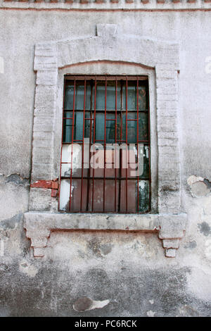 Alte Fenster mit Gittern. Holz- Fenster mit schmutzige Gläser und antiken rostige Gitter mit einer zerrissenen net. Stockfoto