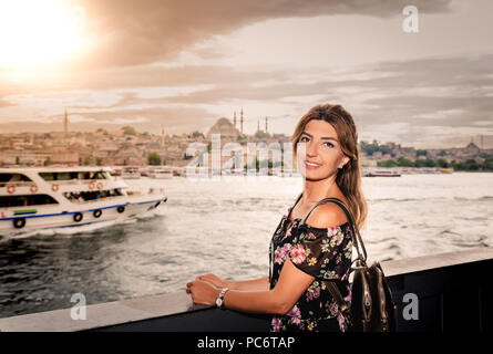 Schöne Frau in schwarzem Kleid steht unter der Galatabrücke mit Landschaft Blick auf Istanbul für den Hintergrund. Stockfoto