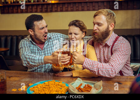 Menschen, Freizeit, Freundschaft und Kommunikation Konzept - glückliche Freunde Bier trinken, Reden und klirren Gläser an der Bar oder pub Stockfoto