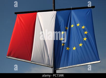 Nationale Flagge Polens und der Flagge der Europäischen Union hängen zusammen, neben einander, auf der Pole Position, im Freien, im Hintergrund blauer Himmel Stockfoto