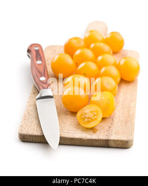Gelbe Kirschtomaten auf Schneidebrett auf weißem Hintergrund. Stockfoto