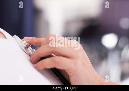 Womans hand mit Stethoskop auf Patienten. Nahaufnahme von zarten weiblichen Hand mit Stethoskop und verschieben es auf Patienten Brust. Stockfoto