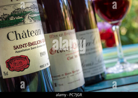 Französische Weinprobe Trinken Sie im Freien Flaschen von feinen roten Bordeaux- und Burgunder-Weinen im Freien auf der sonnigen Terrasse mit Blumenmuster Stockfoto