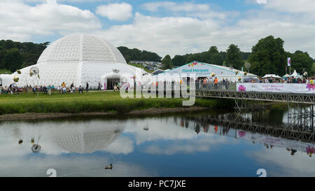 An der RHS Chatsworth Flower Show (Menschen besuchen, Festzelt, Zelte, grosser Wintergarten Dome, Fluss & provisorische Brücke) Derbyshire, England, UK Showground. Stockfoto