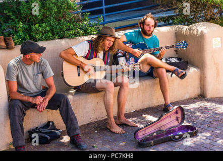 TAOS, NM, USA-8 Juli 18: Zwei Gitarristen und ein geiger auf verbogene St. sitzen, spielen für Tipps. Stockfoto