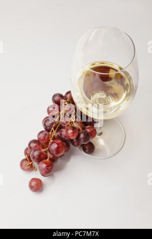 Blick von oben auf die weiße Glas Wein und Trauben auf Weiß Stockfoto