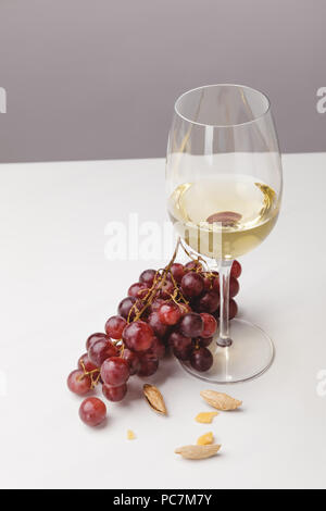 Detailansicht Weißwein Glas, Trauben und Mandeln auf Grau Stockfoto