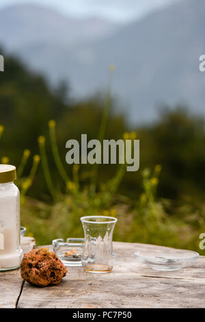 Eine leere Türkischen Tee Glas auf einem Baumstamm Tischplatte vor grüne Landschaft Vista anzeigen. Stockfoto