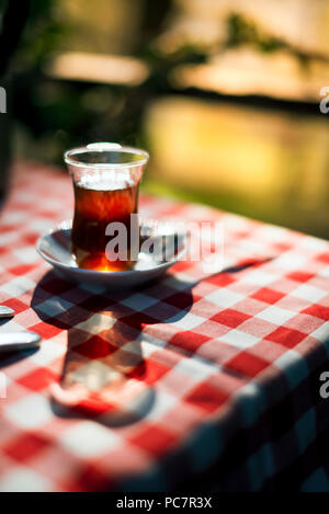 Türkischer Tee auf einem karierten Muster Tischdecke unter direkter Sonneneinstrahlung und Outdoor. Stockfoto