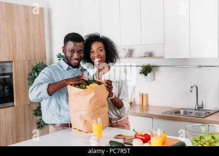 Lächelnd afrikanische amerikanische Paar, die Trauben von Papiertüte mit Früchten Stockfoto