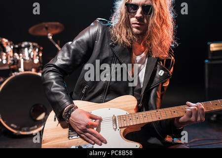 Hübscher Rock-Star in Brillen Hard Rockmusik mit Bass-Gitarre auf der Bühne spielen Stockfoto