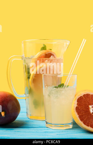 Nahaufnahme der frische reife Mango, Grapefruit und kalten Sommer trinken in Glas und Kanne auf Gelb Stockfoto