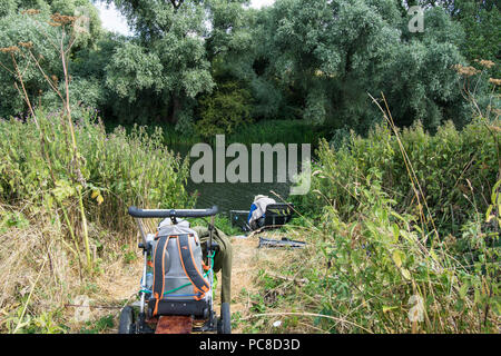 Angler im See im Village Life Olney Bedfordshire Fische Fischen Sie Angeln Buggstuhl Bäume Wassersitz sitzen Mann schlafende Schilf draußen Stockfoto