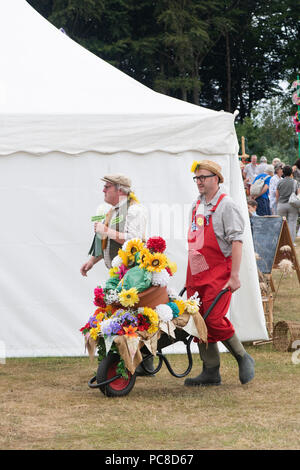 Floral Künstler drücken eine Schubkarre voller Blumen an der RHS Tatton Park Flower Show 2018, Cheshire, Großbritannien Stockfoto