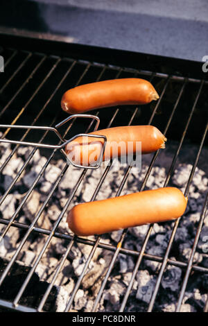 Mit Zange einstellen Würstchen vom Grill im Außenbereich Grill Stockfoto