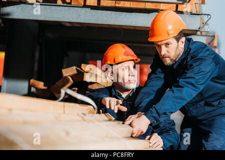 Zwei Erbauer in Helme arbeiten mit Holzbohlen auf Bau Stockfoto