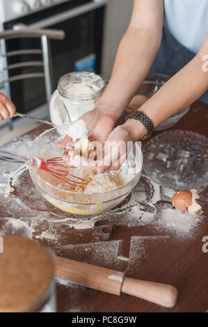 7/8 Schuß von Frau Zubereitung Teig für Cookies über unordentlich Tabelle Stockfoto