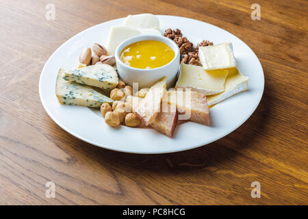 Nahaufnahme der leckeren Käse Platte mit Nüssen und Honig auf hölzernen Tischplatte Stockfoto