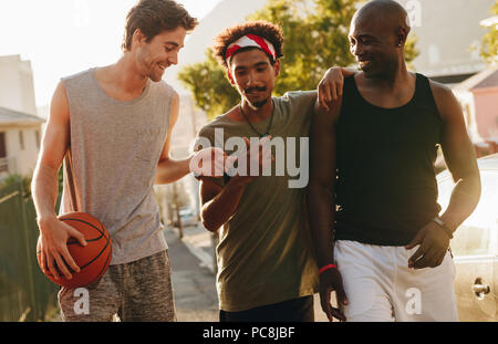 Drei basketball Männer auf der Straße reden und Spaß haben. Männer zu Fuß zurück nach einem Spiel der Basketball. Stockfoto