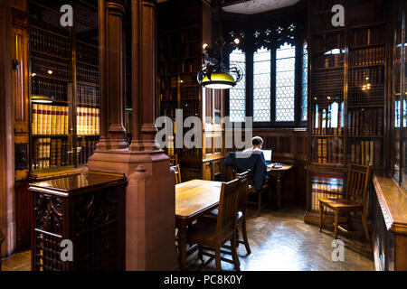 Mann sitzt mit einem Laptop an eine alte Bibliothek recherchieren, studieren, Johny Rylands Library, Manchester, UK Stockfoto