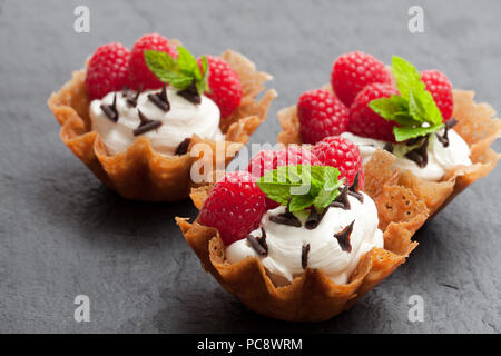 Brandy snap Körbe mit Eis und Beeren auf schwarzen Stein Hintergrund Stockfoto