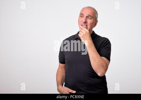 Reifen Hispanic Mann denken mit den Händen auf Kinn weg schauen. Close up Portrait von echten Menschen. Stockfoto