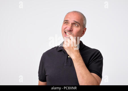 Reifen Hispanic Mann denken mit den Händen auf Kinn weg schauen. Close up Portrait von echten Menschen. Stockfoto
