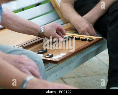Zwei ältere Männer Backgammon spielen auf der Bank in der Straße in der Nähe von Stockfoto