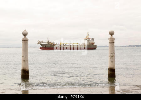 Ein paar der Pombalinischen Säulen der Lissabonner Gateway auf dem Meer, auf den Fluss Tejo mit einem Frachter zwischen den beiden in Portugal zentriert. Stockfoto