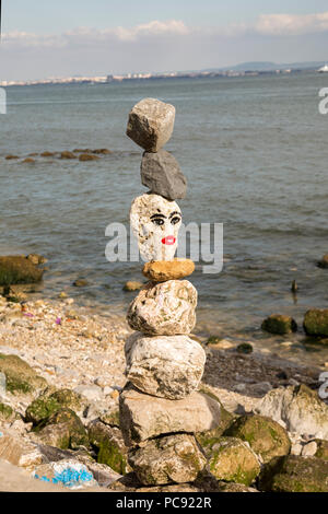 Gestapelte Felsen am Strand in Lissabon, Portugal. Diese Felsen sind auch eingerichtet und haben Gesichter gemalt. Stockfoto