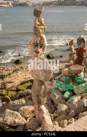 Gestapelte Felsen am Strand in Lissabon, Portugal. Diese Felsen sind auch eingerichtet und haben Gesichter gemalt. Stockfoto