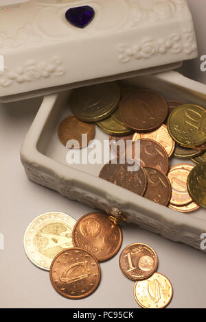 Nahaufnahme eines kleinen weißen Porzellan Bisque schmuck Box und enthält eine Sammlung von Euro-münzen Stockfoto