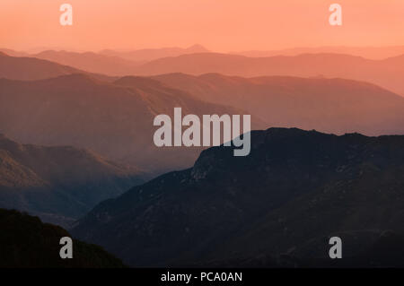 Sonnenuntergang über Bergketten der Sierra Nevada in Kalifornien. Schöne Silhouette mit mehreren ridge Schichten und orange Haze. Malerische Landschaft geschossen. Stockfoto