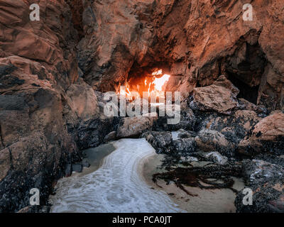 Berühmte Keyhole Arch bei Pfeiffer Strand, entlang des Pacific Coast Highway 1 in Kalifornien. Licht der untergehenden Sonne glänzt durch eine schöne Klippen. Stockfoto