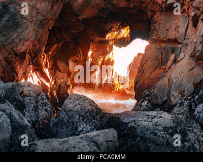 Nahaufnahme von Sonnenlicht durch den Fels Bohrung bei Pfeiffer Beach in der Nähe von Big Sur, Kalifornien. Wave Säurespritzer sind an der Unterseite sichtbar. Stockfoto