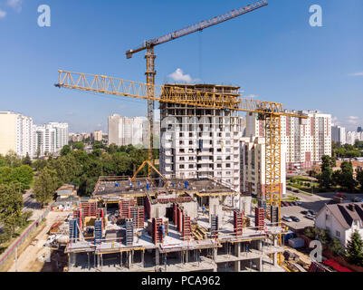 Gelbe Turmdrehkrane im City Baustelle gegen den blauen Himmel Hintergrund arbeiten, Antenne Top View Stockfoto