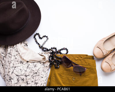 Flach mit der Kleidung der Dame, Hut, Sonnenbrille, Halskette. Herbst Farben Zubehör auf weißem Hintergrund Stockfoto