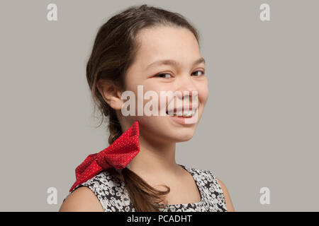 Lächelnde Mädchen mit roter Schleife im Haar und Zahnspangen Stockfoto