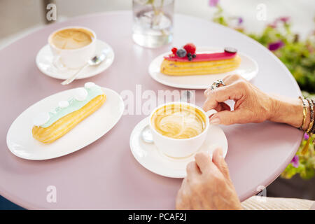 Lickerish eclair und Kaffee auf der Oberfläche Stockfoto