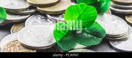 Zerstreut russische Münzen auf grauem Hintergrund mit Blättern von Clover. Viel Glück, St. Patrick's Day Stockfoto