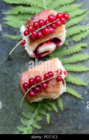 Hausgemachte leckere Hefe Brötchen mit rote Johannisbeeren auf einem Farn Blatt Stockfoto