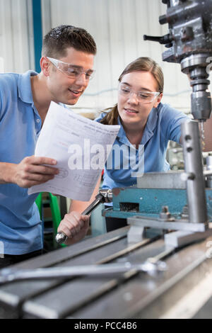 Techniker anweisen weiblichen Lehrling für den Gebrauch von Drill Stockfoto