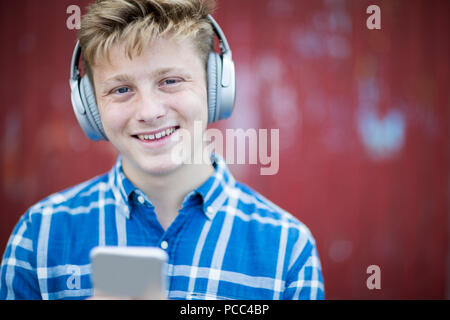 Portrait von Teenager tragen drahtlose Kopfhörer und das Hören von Musik in der städtischen Umgebung Stockfoto