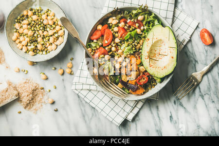 Flachbild-lay von veganen Abendessen Schüssel mit Avocado, Körner, Bohnen, Gemüse Stockfoto