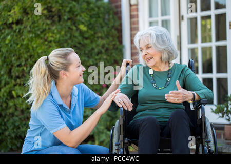 Pflegeperson Drücken ältere Frau im Rollstuhl außerhalb Home Stockfoto