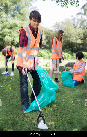 Gruppe von hilfreich Jugendlichen sammeln Müll In der Landschaft Stockfoto
